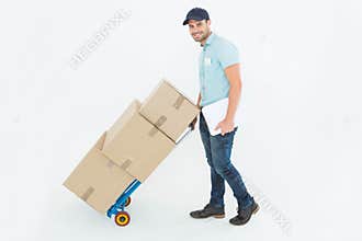 Confident delivery man pushing trolley of boxes