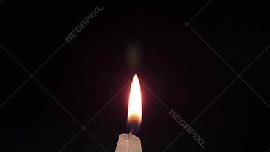 Horizontal footage of a glowing candle flame in dark background