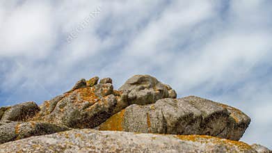 Rock formations in Bretagne under a cloudy sky with patches of blue at midday
