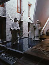 Two white angel statues standing in a modern courtyard prayer room