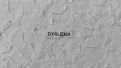 Crumpled piece of paper with word Dyslexia on torn crumpled white paper pieces background. Zoom in