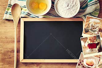 Top view of blackboard and wooden spoon over wooden table and collage of photos with various food and dishes.