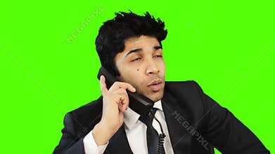 Businessman talking on telephone and showing thumbs up against green background