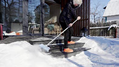 A woman sweeps snow off the steps.