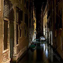 Exploring the canals of Venice at night with boats and reflections in the calm water