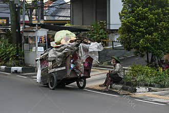 Homeless Man Sitting by Recycling Cart on Bandung City Street in Indonesia