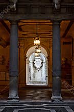 Ornate Lanterns Cast a Warm Glow Between Monumental Columns, Illuminating an Arched Passageway to a White Marble Crest