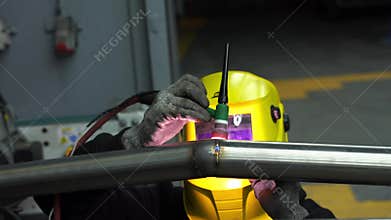 4k video Worker performs TIG welding on metal using a tungsten electrode with argon shielding gas, wearing a protective welding