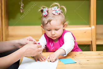 Mother and child girl playing in kindergarten in Montessori preschool