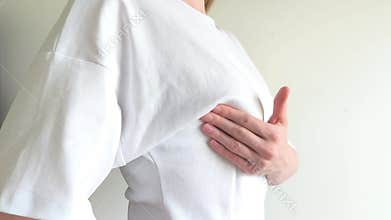 Woman checks her breast for lumps using her hand during