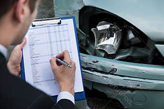 Insurance agent examining car after accident