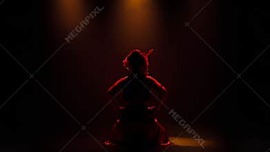 Dramatic Silhouette of Traditional Dancer Under Red Stage Lighting