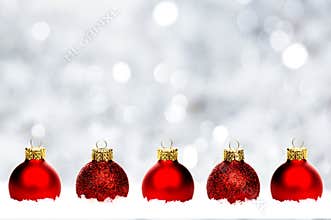 Red Christmas baubles in snow with silver background