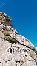 Limestone cliff with shrubs and clear blue sky