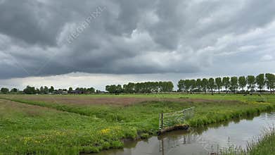 Rural Amsterdam, Dutch farmland under heavy low cloud deck with canal and