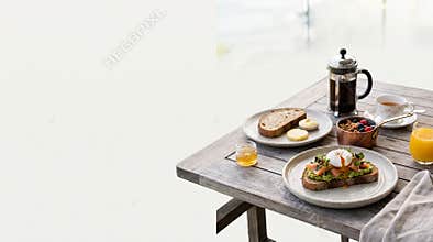 A hearty morning meal featuring poached egg toast with smoked salmon and aromatic coffee sits on a rustic wooden table