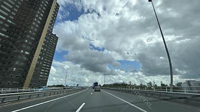 Curved urban motorway beside tall residential tower under dramatic cloudy sky