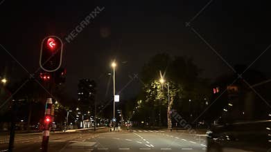Night street intersection with red traffic light, illuminated trees, tram tracks