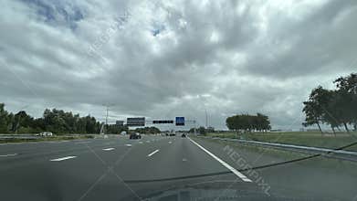 Wide motorway view from moving car with multiple vehicles, overhead road signs