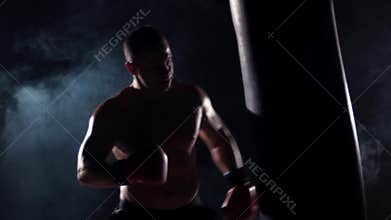 Boxer man during boxing hiting heavy bag at