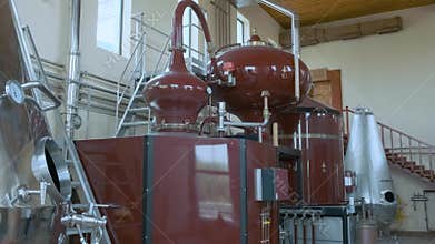 Brandy distillery with large red fermentation tanks with copper piping and gauges. Distiller for alcohol production of