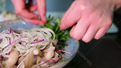 Marinated mushrooms parsley garnish olive oil female hands blue plate closeup appetizer