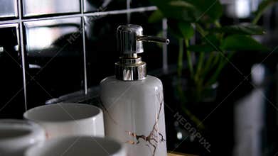 Luxury bathroom accessories set white marble soap dispenser cups on black tiles premium spa interior close-up elegant