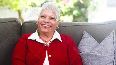 Happy Senior Woman Joyfully Smiling and Laughing on a Comfortable Couch at Home