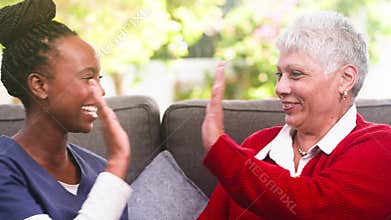 Joyful Interaction: Caregiver and Senior Woman Share a Happy Digital Moment