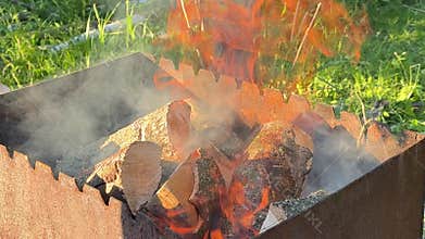 Firewood added into metal barbecue grill during campfire ignition process for outdoor cooking and ??????