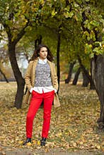 Young woman in fashion coat walking in autumn park