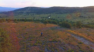 Aerial view of lone hiker trekking bushy hillside trail above green valley and ridgeline, path, backpacker, solitary, backpacking