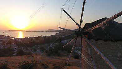 Aerial drone circles historic stone windmill above Foca at sunset on Aegean coast in Turkiye, historic mill, stone tower, izmir