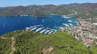 Aerial drone view of Gocek marina and forested bay with boats homes and vivid blue sea, yachts, coastal town, mugla, turkiye
