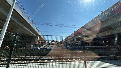 Urban transport construction site beneath elevated roadway with metal fence