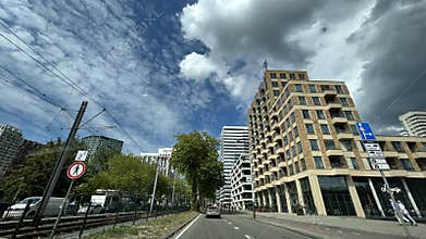 Modern residential towers beside tram tracks and roadway under dramatic cloudy