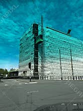 Wrapped high-rise building under renovation beside wide city street with