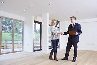 Woman Shaking Hands With Estate Agent In New Home