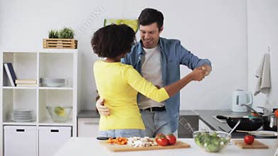 Happy couple cooking food and dancing at home