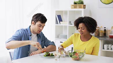 Happy couple eating vegetable salad at home