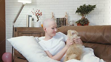 Cancer patient woman lying on the sofa and playing with a little cute dog