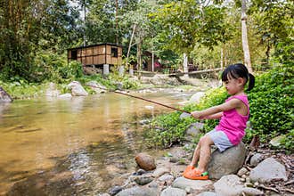 Happy Asian Chinese little girl angling with fishing rod