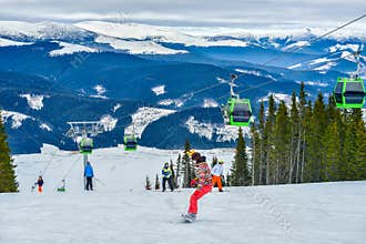 Cable car gondola ski lift and skiers on the slope in Voineasa, Romania