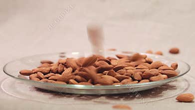 Almonds falling down into glass bowl