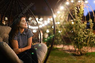 Lovely girl pensively looks aside and smiles sweetly, sitting in