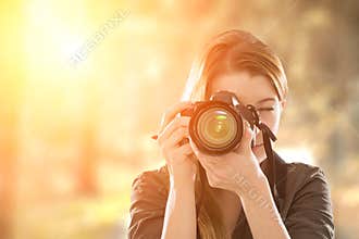 Portrait of a photographer covering her face with camera.