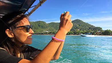 Young Happy Girl Sails on a Boat and Take Pictures on smart phone. Krabi, Thailand.