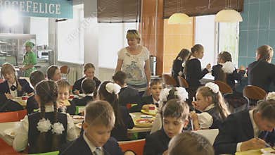 Teacher Walks between Tables and Look at Pupils Eat Lunch