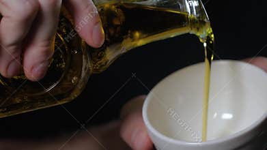 Bottle pouring italian virgin olive oil in a bowl close up