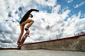 A young skateboarder makes Wallie in a skatepark, jumping on a skateboard into the air with a coup